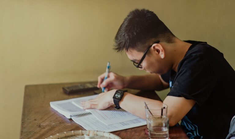 Student studying with a laptop and notebook, using AI tools to help with schoolwork